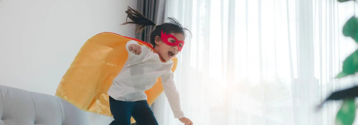 Child playing superhero at home, building confidence through imaginative play