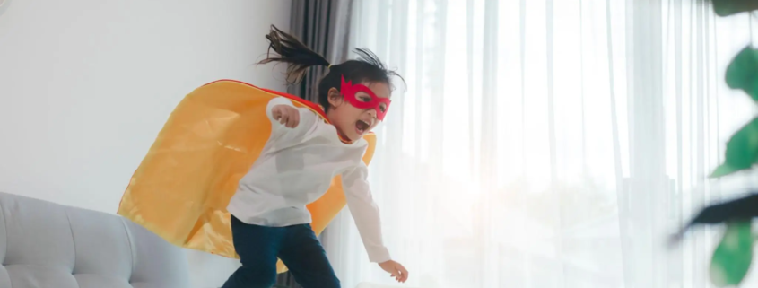 Child playing superhero at home, building confidence through imaginative play